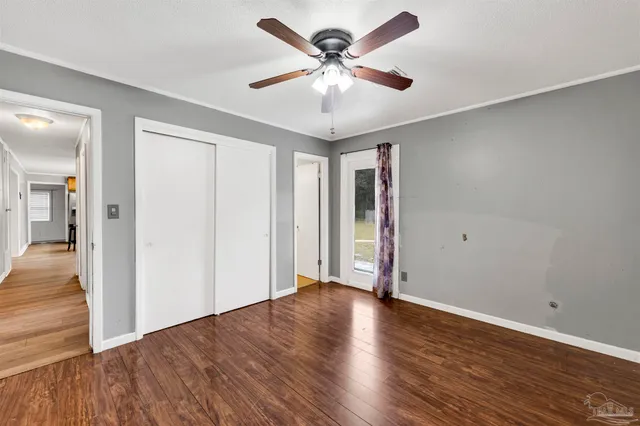 an empty room with wooden floor and ceiling fan