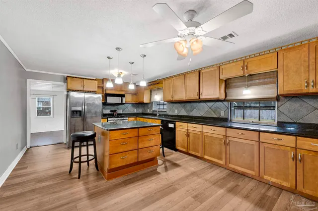 a kitchen with stainless steel appliances kitchen island granite countertop a stove a sink and a microwave