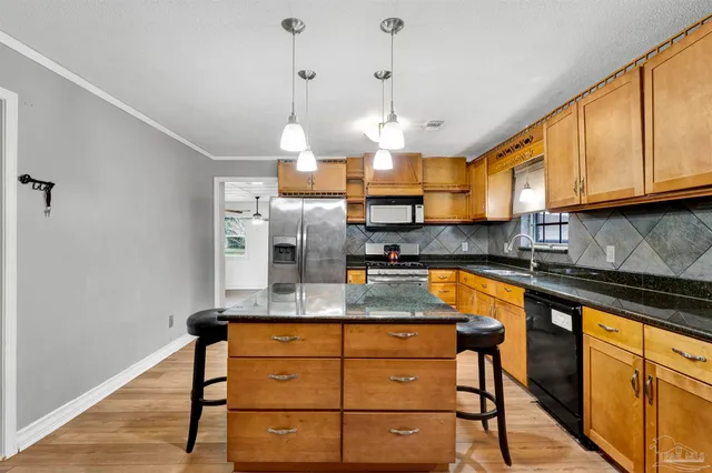 a kitchen with stainless steel appliances granite countertop a sink a stove and a wooden floors