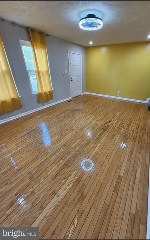 a view of empty room with window and wooden floor