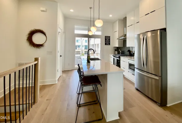 a kitchen with stainless steel appliances wooden floor dining table and chairs
