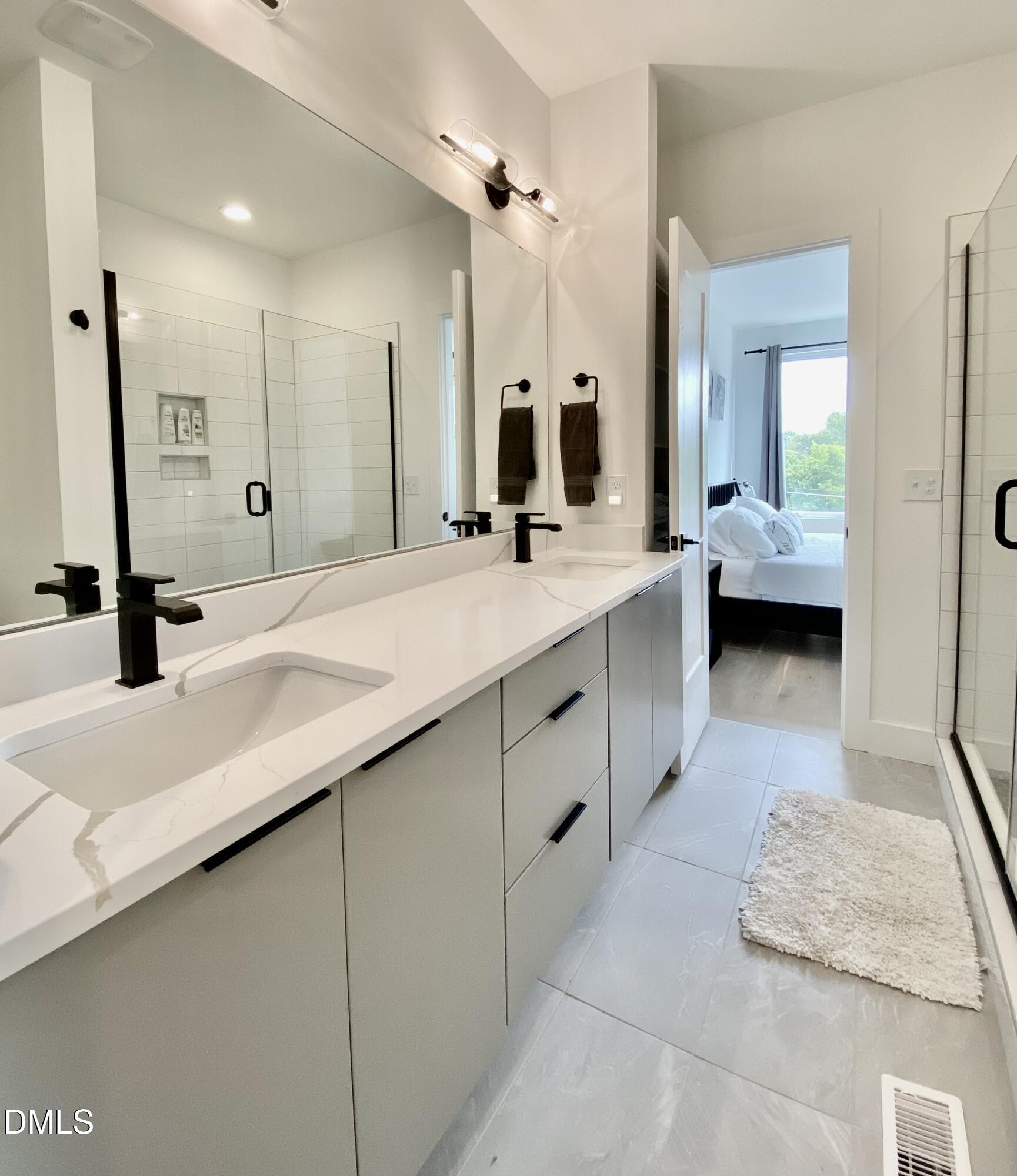 629 North Queen Street Durham, NC 27701 - Photo 44 of 58 a large bathroom with a double vanity sink a large mirror and shower