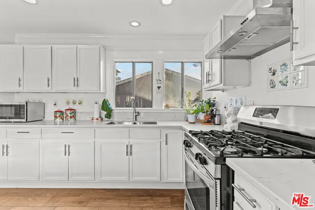 a kitchen with stainless steel appliances a stove a white cabinets and a sink