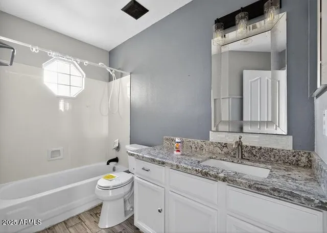 a bathroom with a granite countertop sink a toilet and bathtub