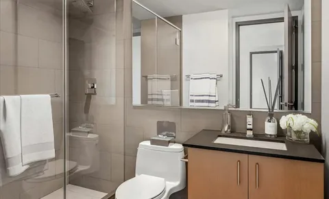 a bathroom with a granite countertop sink toilet and mirror