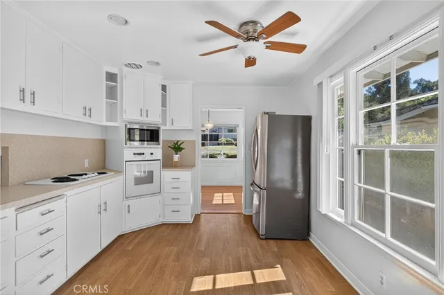 a kitchen with granite countertop a refrigerator a sink and white cabinets