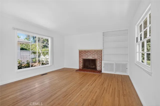 a view of empty room with wooden floor and fireplace