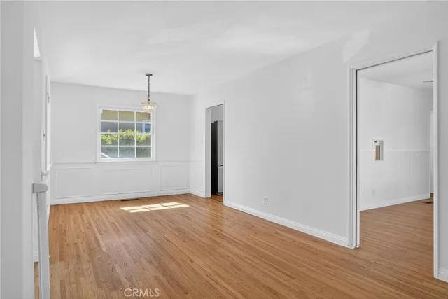 an empty room with wooden floor cabinet and windows