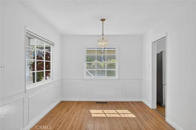 an empty room with wooden floor exposed radiator and windows
