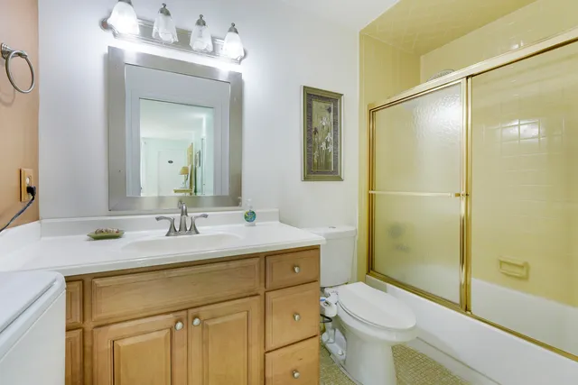 a bathroom with a granite countertop sink toilet mirror and shower