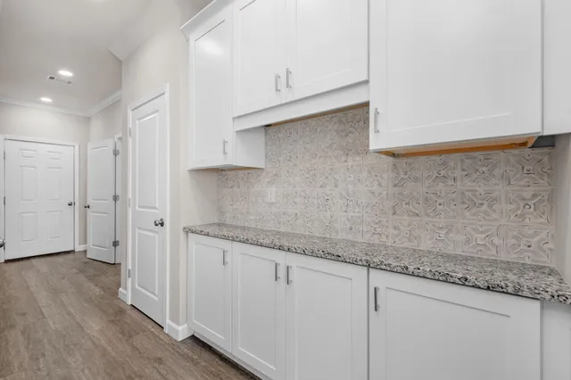 a large white kitchen with granite countertop a sink window and a counter space