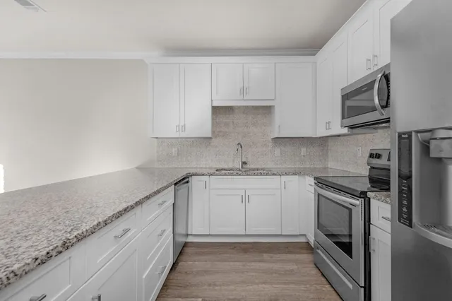 a kitchen with granite countertop white cabinets stainless steel appliances and a sink