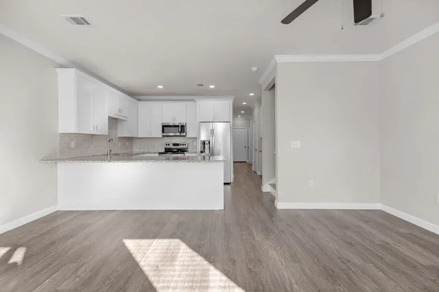 a kitchen with granite countertop cabinets stainless steel appliances a sink and wooden floor