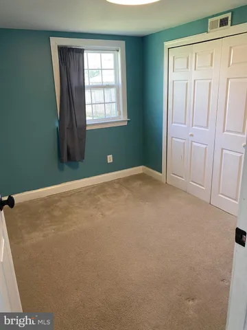 an empty room with wooden floor fireplace and windows