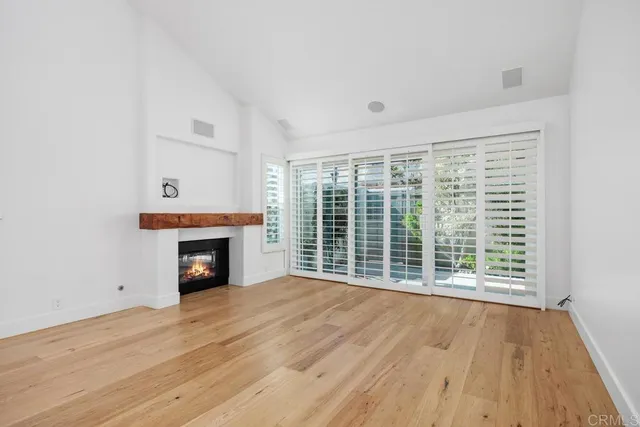 a view of empty room with wooden floor and fireplace