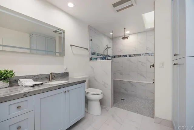 a bathroom with a granite countertop sink a toilet and shower