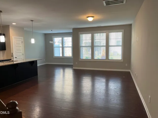 an empty room with wooden floor closet and windows