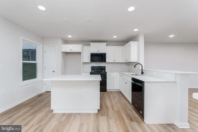 a large kitchen with cabinets wooden floor and stainless steel appliances