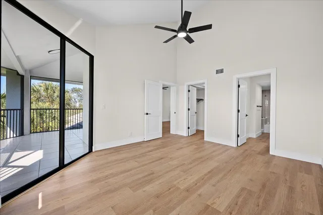 a view of empty room with wooden floor and fan