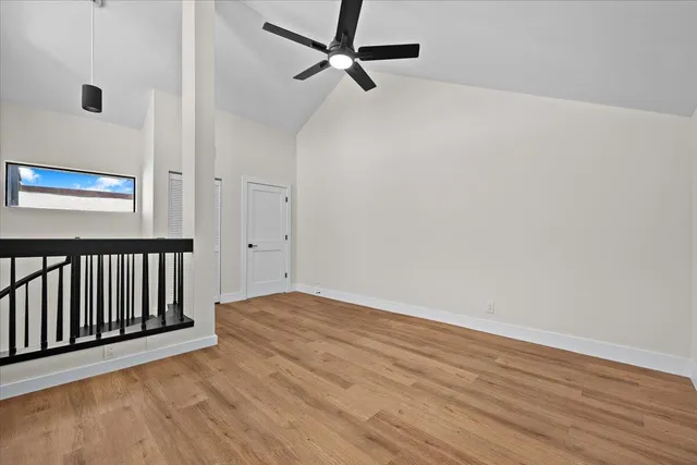 a view of an empty room with a window and wooden floor