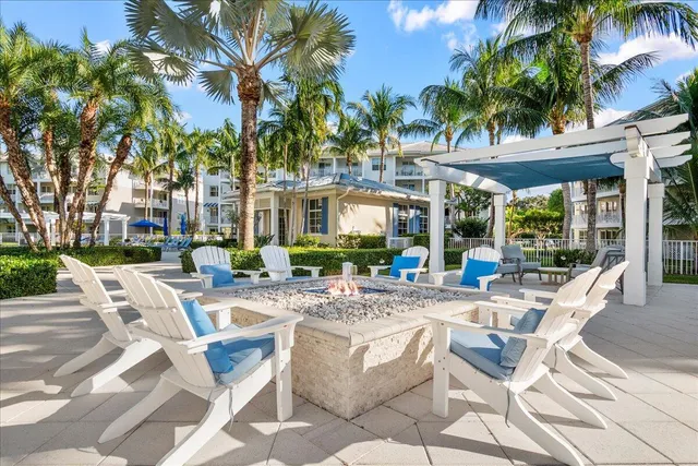 a view of a patio with a dining table and chairs under palm trees