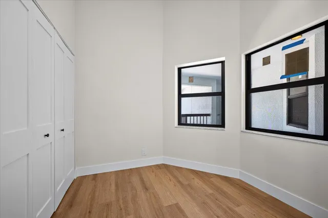 a view of an empty room with wooden floor and a window