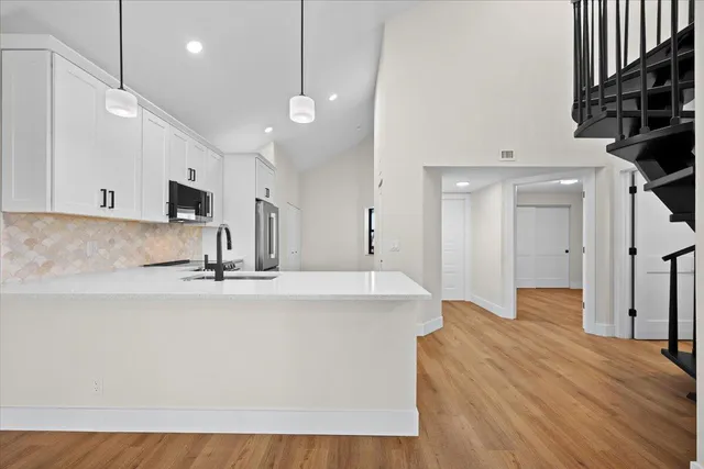 a large white kitchen with a large island oven a sink stainless steel appliances and cabinets