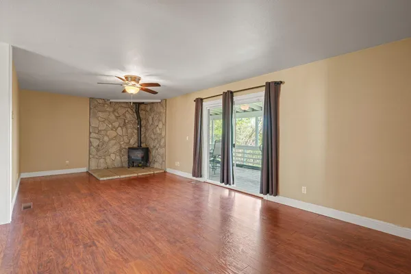 a view of an empty room with wooden floor and a fireplace