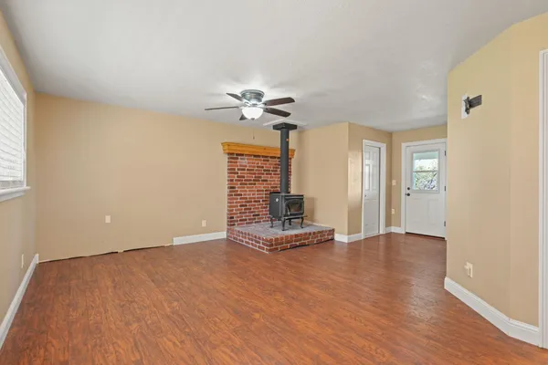 a view of an empty room with wooden floor and a ceiling fan
