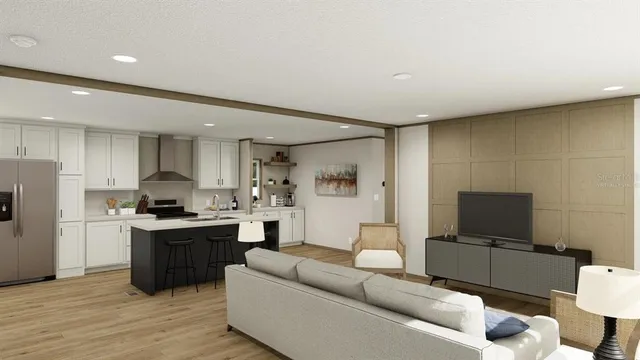 a living room with stainless steel appliances furniture and a flat screen tv