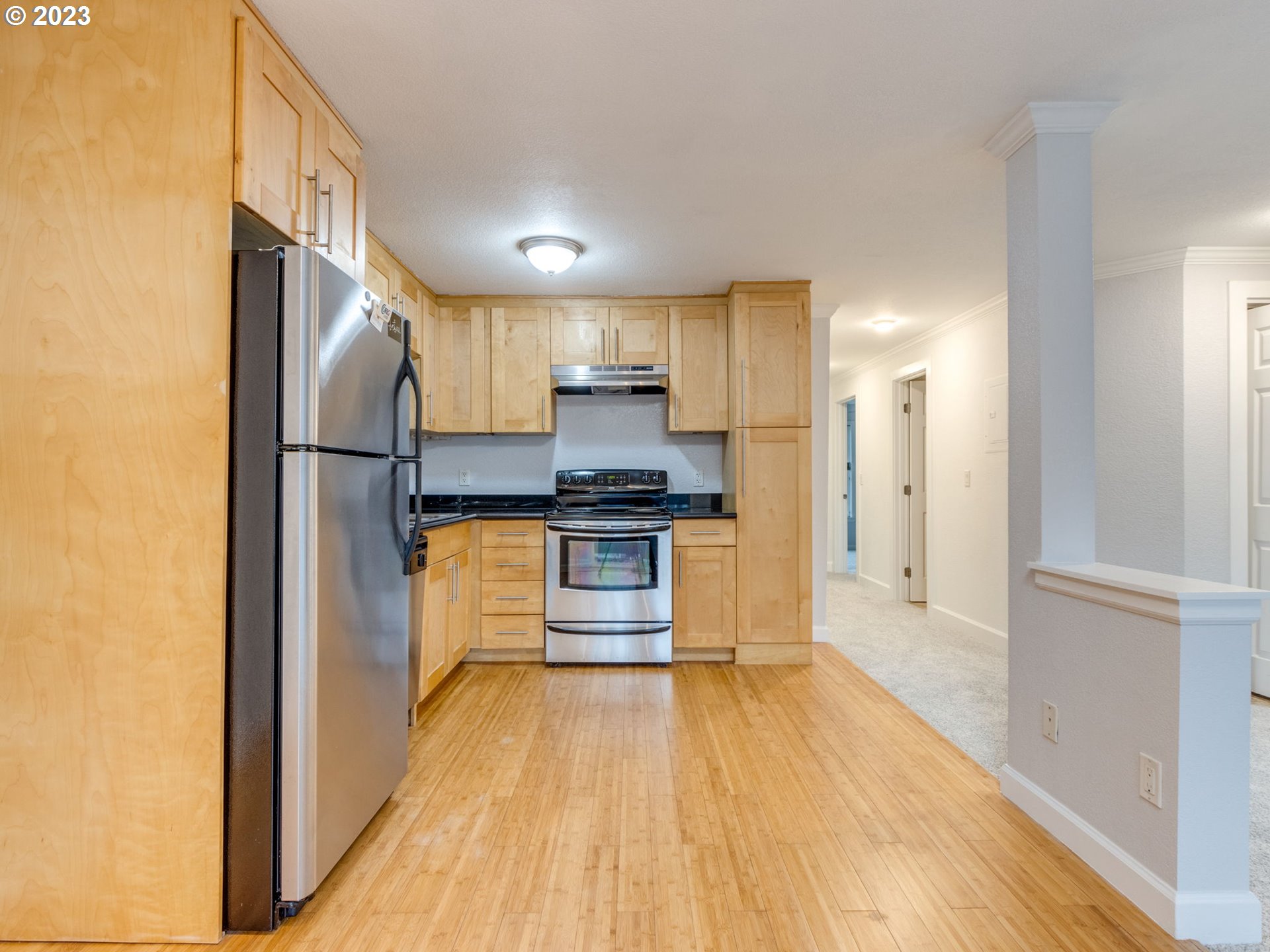 7937 Southwest 40th Avenue, Unit F Portland, OR 97219 - Photo 9 of 36 a kitchen with a refrigerator and white cabinets