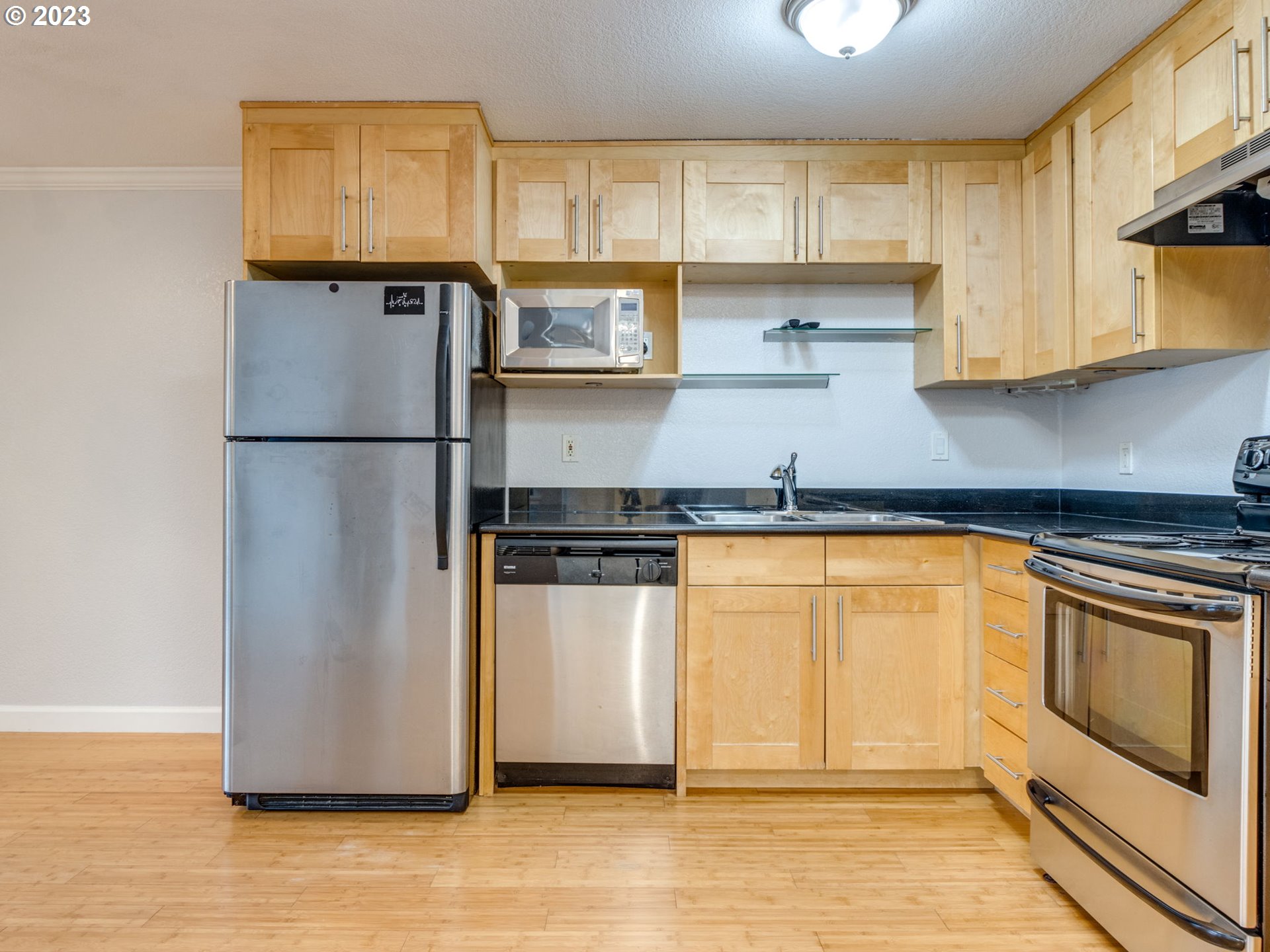 7937 Southwest 40th Avenue, Unit F Portland, OR 97219 - Photo 10 of 36 a kitchen with stainless steel appliances granite countertop a refrigerator a stove a sink and a microwave