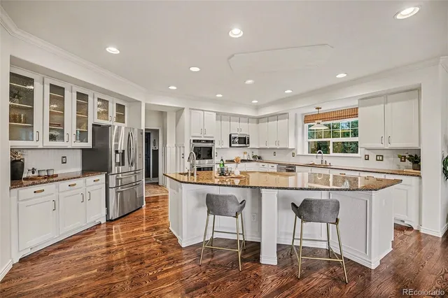 a kitchen with stainless steel appliances granite countertop a table chairs sink refrigerator and cabinets