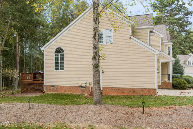 a view of a white house next to a yard with large trees
