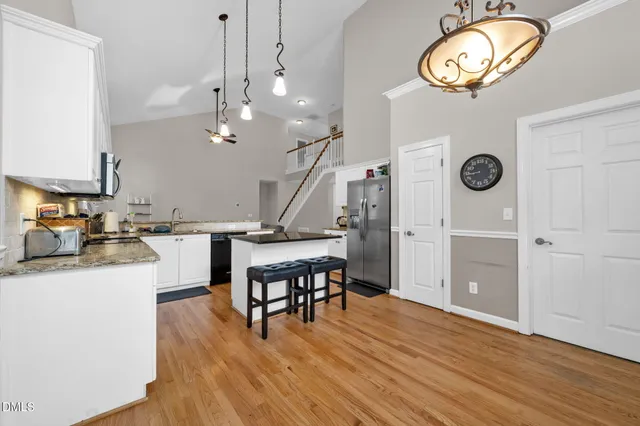 a view of a kitchen and an empty room with wooden floor