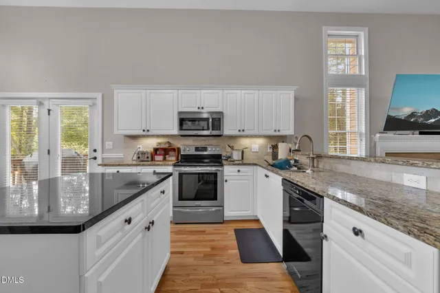 a kitchen with kitchen island granite countertop a sink appliances cabinets and a counter top space