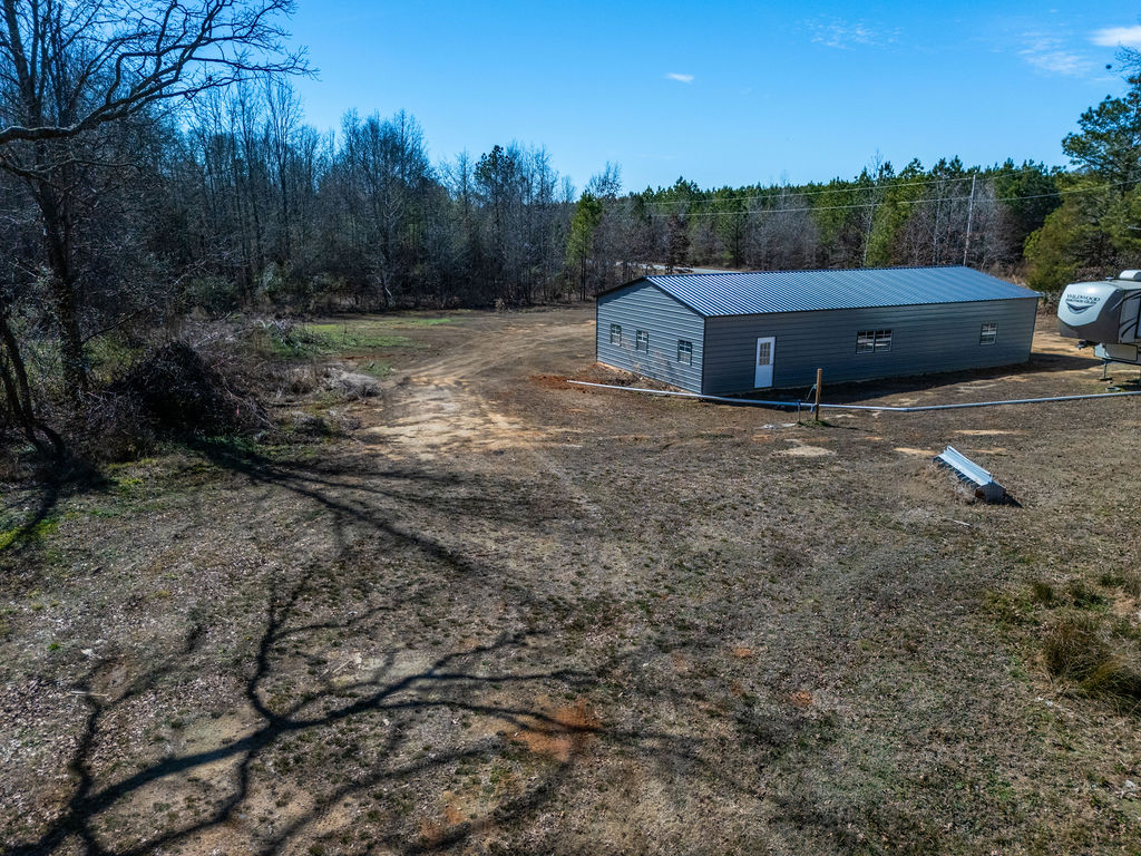 900 Asaville School Road Anderson, SC 29621 - Photo 28 of 29 This expansive lot features a durable metal structure amidst a rustic, natural landscape.