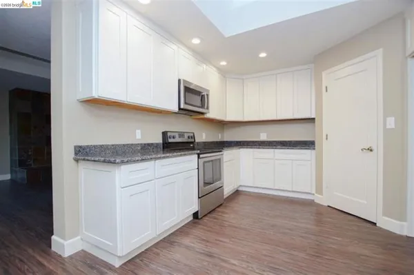 a kitchen with granite countertop white cabinets and white appliances
