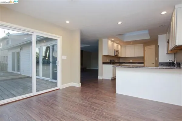 a view of kitchen with granite countertop stainless steel appliances counter space and wooden floor