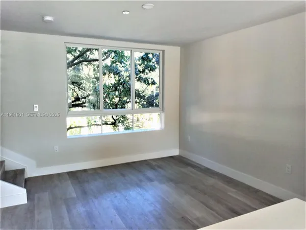 an empty room with wooden floor and a window