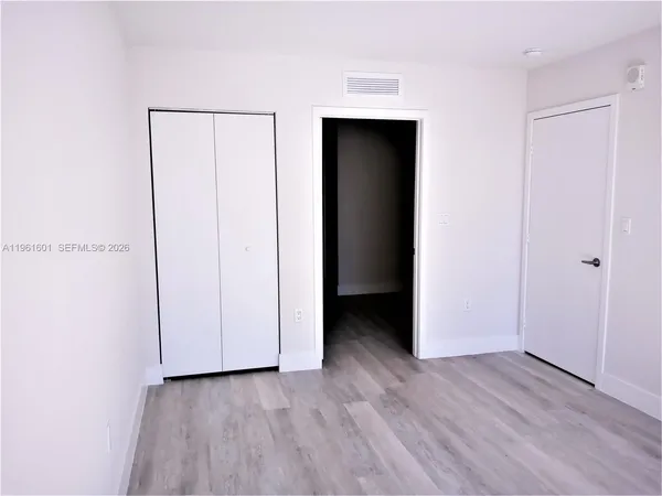 a view of an empty room with closet and a window