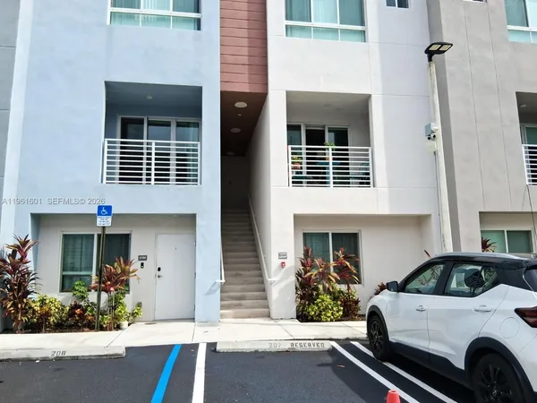 a view of a house with a cars park side of a road