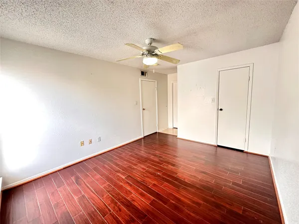 an empty room with wooden floor ceiling fan and window