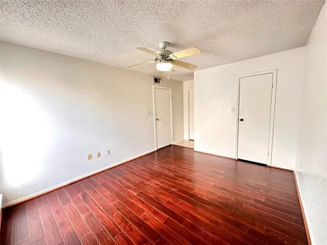 an empty room with wooden floor ceiling fan and window