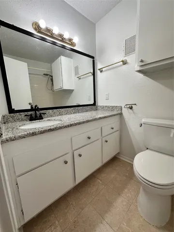 a bathroom with a granite countertop sink a toilet and a mirror