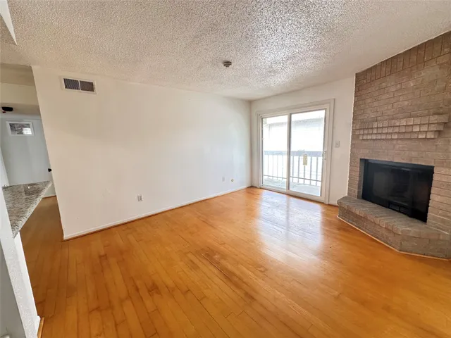a view of empty room with wooden floor and fireplace