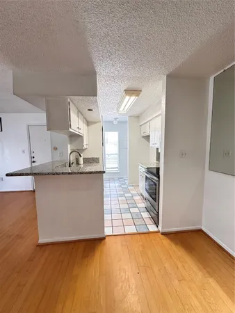a view of kitchen with granite countertop cabinets and refrigerator