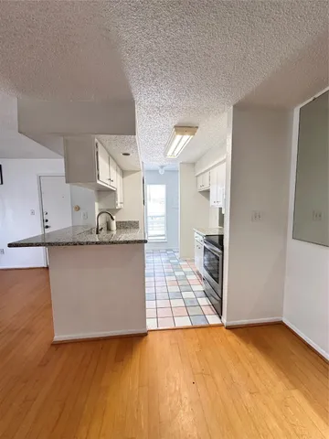a view of kitchen with granite countertop cabinets and refrigerator