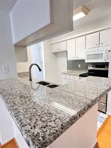 a kitchen with kitchen island granite countertop a sink stove and white cabinets