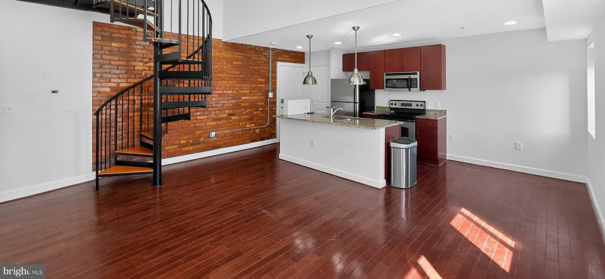 a kitchen with stainless steel appliances kitchen island wooden floors and view living room